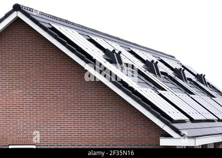 Pannelli solari montati sul tetto di una moderna casa di nuova costruzione a Lemmer, Friesland, Paesi Bassi con cielo blu nuvoloso. Energia sostenibile Foto Stock