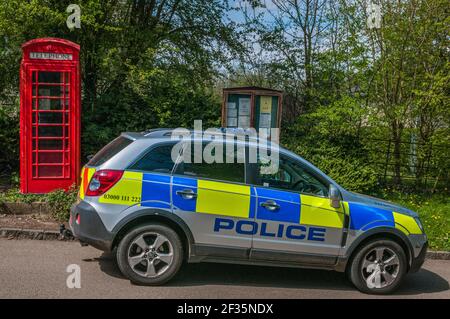 Northamptonshire, Inghilterra, Regno Unito. un'auto di polizia 4x4 parcheggiata in un villaggio rurale presso la cassetta del telefono Foto Stock