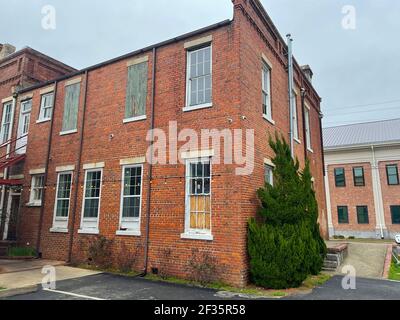 Wayesboro, GA Stati Uniti d'America - 02 11 21: Vecchio dipinto bianco mattone edificio facciata vacanza luci alberi Foto Stock