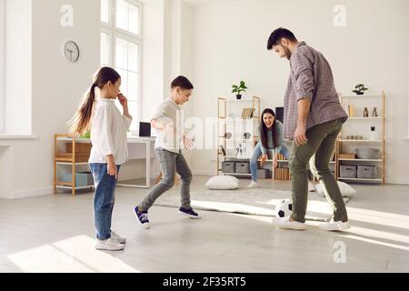 Felice famiglia che gioca palla di calcio al coperto divertirsi durante la quarantena blocco Foto Stock