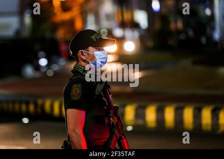 (210315) -- MANILA, 15 marzo 2021 (Xinhua) -- UN poliziotto è visto ad un punto di controllo durante l'attuazione di rigorose misure di quarantena a Manila, nelle Filippine, il 15 marzo 2021. Metro Manila, che ospita circa 13 milioni di persone, ha iniziato ad imporre di nuovo severe misure di quarantena il lunedì per contenere una recente ondata di infezioni da coronavirus. Il Dipartimento di Salute delle Filippine (DOH) ha riferito lunedì che 5,404 nuove infezioni da coronavirus (COVID-19), il più alto numero giornaliero in sette mesi, portando il numero totale di casi confermati nel paese a 626,893. (Xinhua/Rouelle Uma Foto Stock