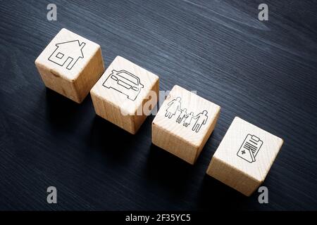 Cubetti di legno con simboli di assicurazione auto, casa, famiglia e medica. Foto Stock