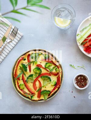 omelette di verdure con broccoli, peperone e rucola su sfondo grigio in pietra. colazione dietetica. vista dall'alto, immagine verticale. Foto Stock