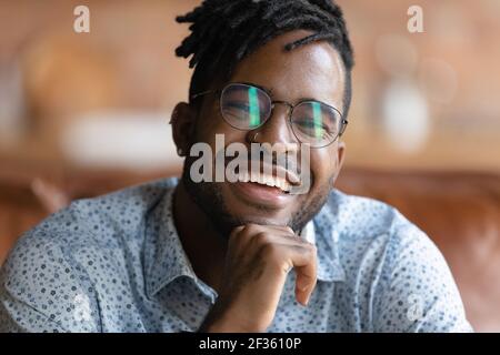 Il giovane maschio africano in occhiali mostra denti forti nel sorriso Foto Stock