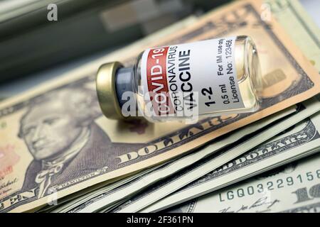Vaccino Covid-19 accanto a diverse banconote da dollaro, immagine concettuale Foto Stock