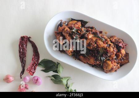 Chicken Chili fatti in casa preparato in stile desi con 5 ingredienti. Una semplice ricetta di pollo con peperoncini rossi interi, scalogni, foglie di curry, cocco oi Foto Stock