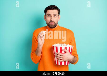 Foto di giovane ragazzo impaurito paura mangiare spaventato popcorn orologio pellicola horror isolata su sfondo di colore teal Foto Stock