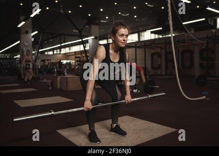 Donna atletica che lavora con il barbell in palestra Foto Stock