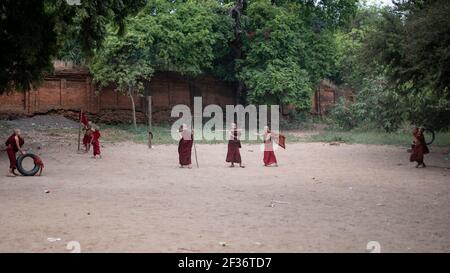 BAGAN, NYAUNG-U, MYANMAR - 2 GENNAIO 2020: Alcuni giovani monaci gioca un gioco attraverso un pneumatico e gettando bastoni attraverso di esso Foto Stock