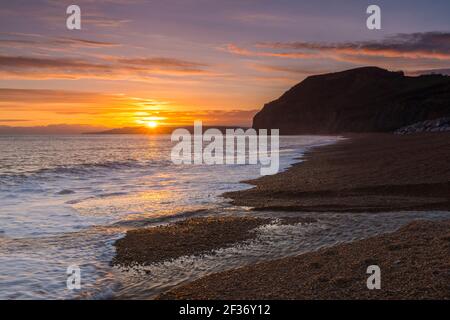 Seatown, Dorset, Regno Unito. 15 marzo 2021. Regno Unito Meteo. Un tramonto spettacolare visto dalla spiaggia che guarda verso le scogliere di Golden Cap a Seatown sulla Dorset Jurassic Coast, come i cieli si stagliano dopo una giornata per lo più sovrastata durante la chiusura del Covid-19. Picture Credit: Graham Hunt/Alamy Live News Foto Stock