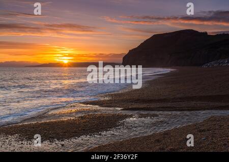 Seatown, Dorset, Regno Unito. 15 marzo 2021. Regno Unito Meteo. Un tramonto spettacolare visto dalla spiaggia che guarda verso le scogliere di Golden Cap a Seatown sulla Dorset Jurassic Coast, come i cieli si stagliano dopo una giornata per lo più sovrastata durante la chiusura del Covid-19. Picture Credit: Graham Hunt/Alamy Live News Foto Stock