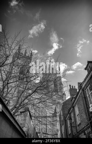 West Towers of York Minster sorge sopra le case di una strada vicina. Un cielo con nuvole è sopra. Foto Stock