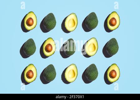 Composizione simmetrica di fette di avocado su sfondo blu. Vista dall'alto. Foto Stock