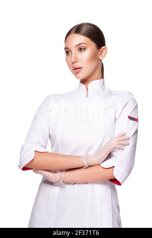 Beauty medico femminile che indossa in uniforme e lattice guanti medici. Donna cosmetologa con un viso serio isolato su sfondo bianco. Trea estetica Foto Stock