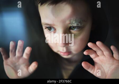 Povero ragazzo triste con sopracciglia tagliata in piedi in casa, concetto di povertà. Foto Stock