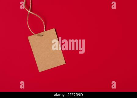 Etichetta di carta marrone Craft isolata su sfondo rosso. Banner prezzo di vendita con spazio di copia in stile minimale Foto Stock