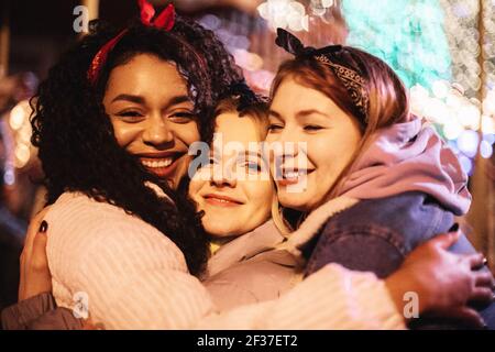 Primo piano ritratto di felici amici femminili che abbracciano la città di notte Foto Stock