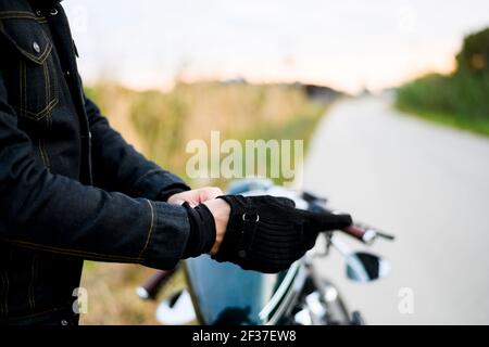 Uomo che indossa i guanti dal sedile di un classico moto Foto Stock