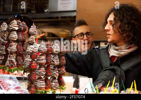 BARCELLONA, SPAGNA - 10 MARZO 2018: I giovani comprano spiedini di fragola freschi ricoperti di cioccolato dallo stallone di frutta al famoso mercato alimentare di Barcellona la Boquer Foto Stock