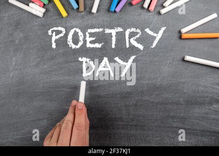 Giornata Mondiale della Poesia 21 marzo. Lavagna scura con pezzi di gesso colorati. Foto Stock