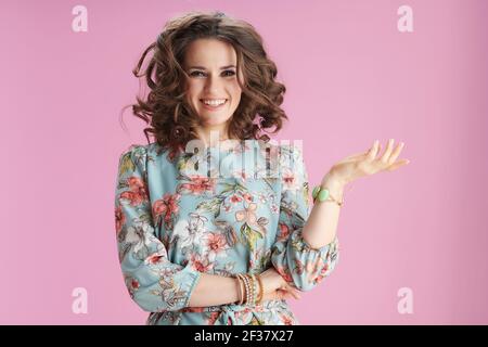 felice giovane donna in abito floreale saltando isolato su rosa. Foto Stock