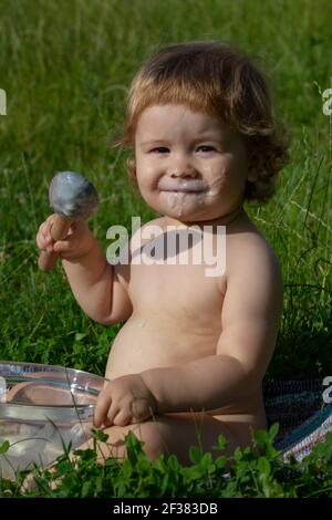 Il bambino piccolo carino sta alimentando usando il cucchiaio. Infanzia spensierata nel villaggio. Foto Stock