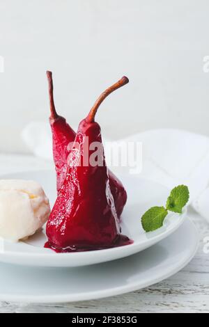 Piatto di gustose pere in camicia in salsa di vino alla luce sfondo di legno Foto Stock