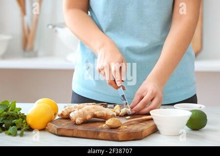 Donna che taglia lo zenzero sul tavolo in cucina Foto Stock