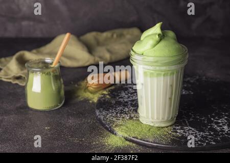 Composizione con gustoso latte matcha dalgona su sfondo scuro Foto Stock