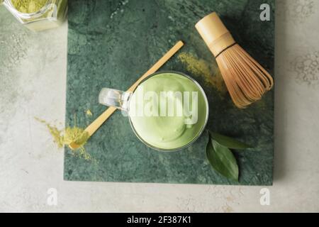 Composizione con gustoso latte di dalgona matcha sul tavolo Foto Stock