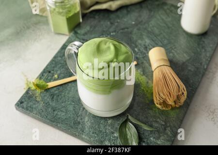 Composizione con gustoso latte di dalgona matcha sul tavolo Foto Stock