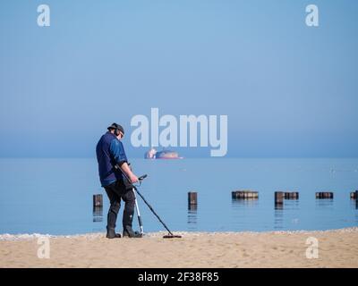 Beachcomber con rilevatore di metalli. Harrison-Dever presa d'acqua presepe in distanza. North Avenue Beach, Chicago, Illinois. Foto Stock