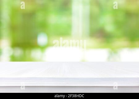Piano tavolo in legno bianco su sfondo astratto verde sfocato - può essere utilizzato per il montaggio o la visualizzazione dei prodotti Foto Stock