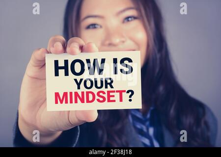 COME STA LA VOSTRA MENTALITÀ? messaggio sulla carta mostrato da una donna, tono vintage Foto Stock