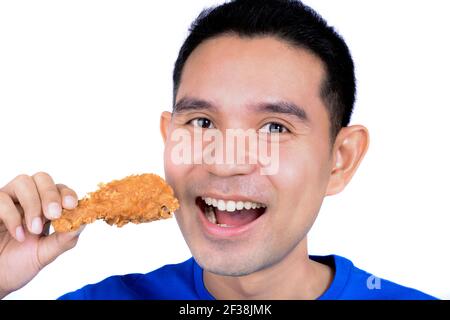 Giovane uomo che mangia pollo fritto Foto Stock