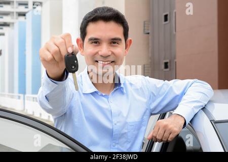 Uomo asiatico sorridente che mostra la chiave dell'auto (volto a fuoco) Foto Stock