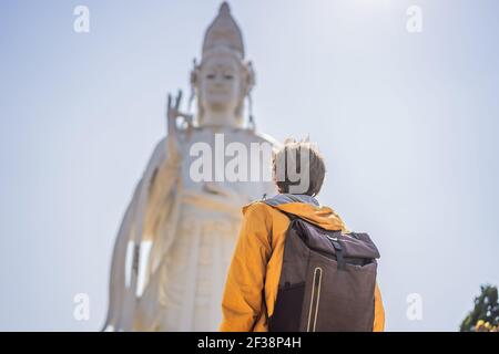 Turista maschile sullo sfondo di Majestic vista della statua di Buddha la Bodhisattva di Misericordia, Vietnam. Statua bianca di Ladybuddha su cielo blu Foto Stock