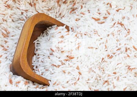 Primo piano su una tazza di legno su un mix di riso bianco con sfondo di riso rosso. Foto Stock