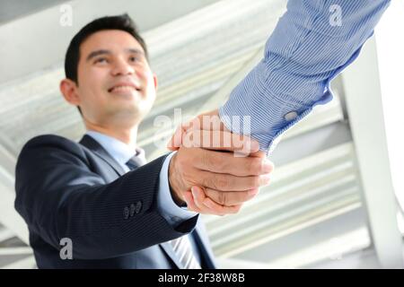 Uomini d'affari che fanno stretta di mano con faccia sorridente - saluto, trattare, fusione e concetti di acquisizione Foto Stock