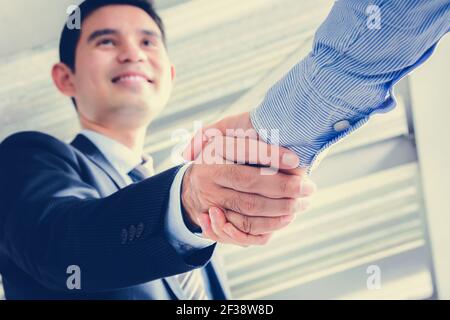 Uomini d'affari asiatici che fanno stretta di mano con faccia sorridente - saluto, trattare, fusione e concetti di acquisizione Foto Stock