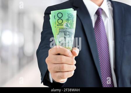Businessman mano che detiene denaro, dollari australiani (AUD) banconote - finanziario, successo degli investimenti e redditizio business concetti Foto Stock