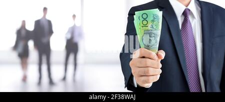 Businessman mano detenere denaro, dollari australiani (AUD) banconote - background finanziario e di investimento panorama Foto Stock