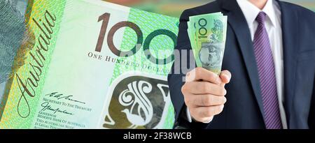 Businessman holding money, dollari australiani (AUD), su 100 note di fondo - concetto di panorama finanziario e di investimento Foto Stock