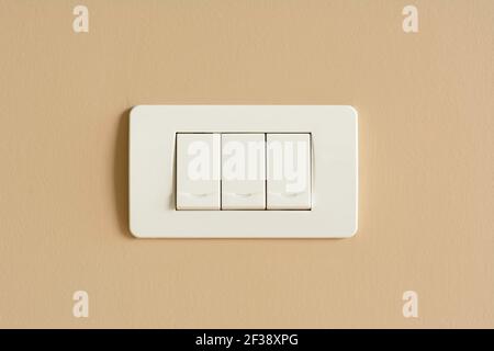 Interruttori a tre luci su parete in cemento colorato Foto Stock