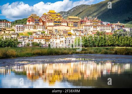 Ganden Sumtseling monastero con bella riflessione d'acqua sul lago in Shangri-la Yunnan Cina Foto Stock