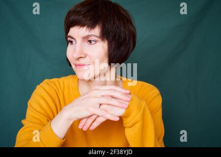 Donna bruna matura sorridente che guarda via giocoso e defiante, faccia ravvicinata Foto Stock
