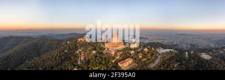 Vista aerea del drone della Basilica del Sacro cuore sulla cima Di Tibidabo vicino Barcellona durante il tramonto in Spagna inverno Foto Stock