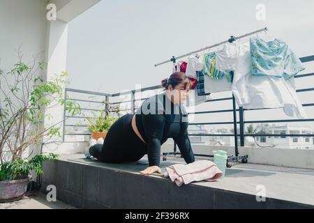 Concetto di salute, fitness e sport. Più la taglia giovane donna asiatica che fa l'esercitazione sul tappeto in balcone, andando perdere le libbre supplementari a casa, diventa forte a. Foto Stock