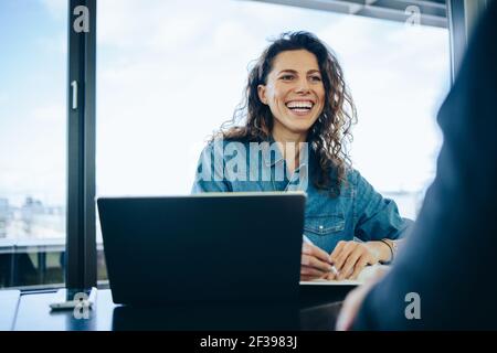 donna d'affari che partecipa a un colloquio di un candidato in una sala riunioni d'ufficio. Reclutatore sorridente che fa domande a un candidato maschio durante il colloquio di lavoro. Foto Stock