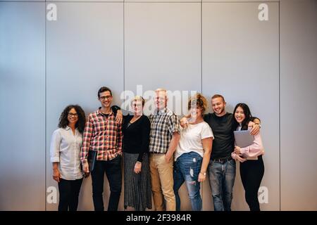 Gruppo di professionisti aziendali multirazziali in piedi insieme. Ritratto di un team aziendale di successo in piedi contro un muro. Foto Stock